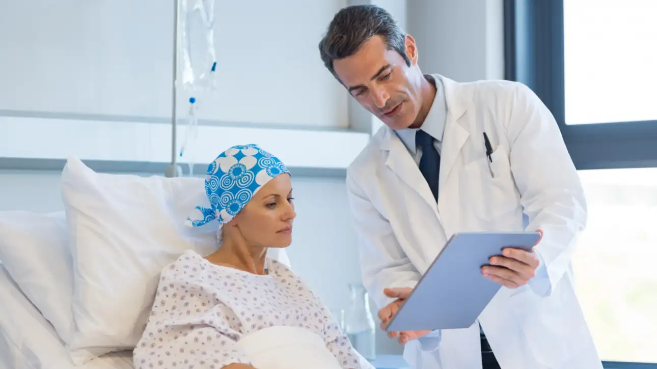 Oncologist reviewing OGSIVEO nirogacestat treatment data on a tablet with a desmoid tumor patient in a hospital room